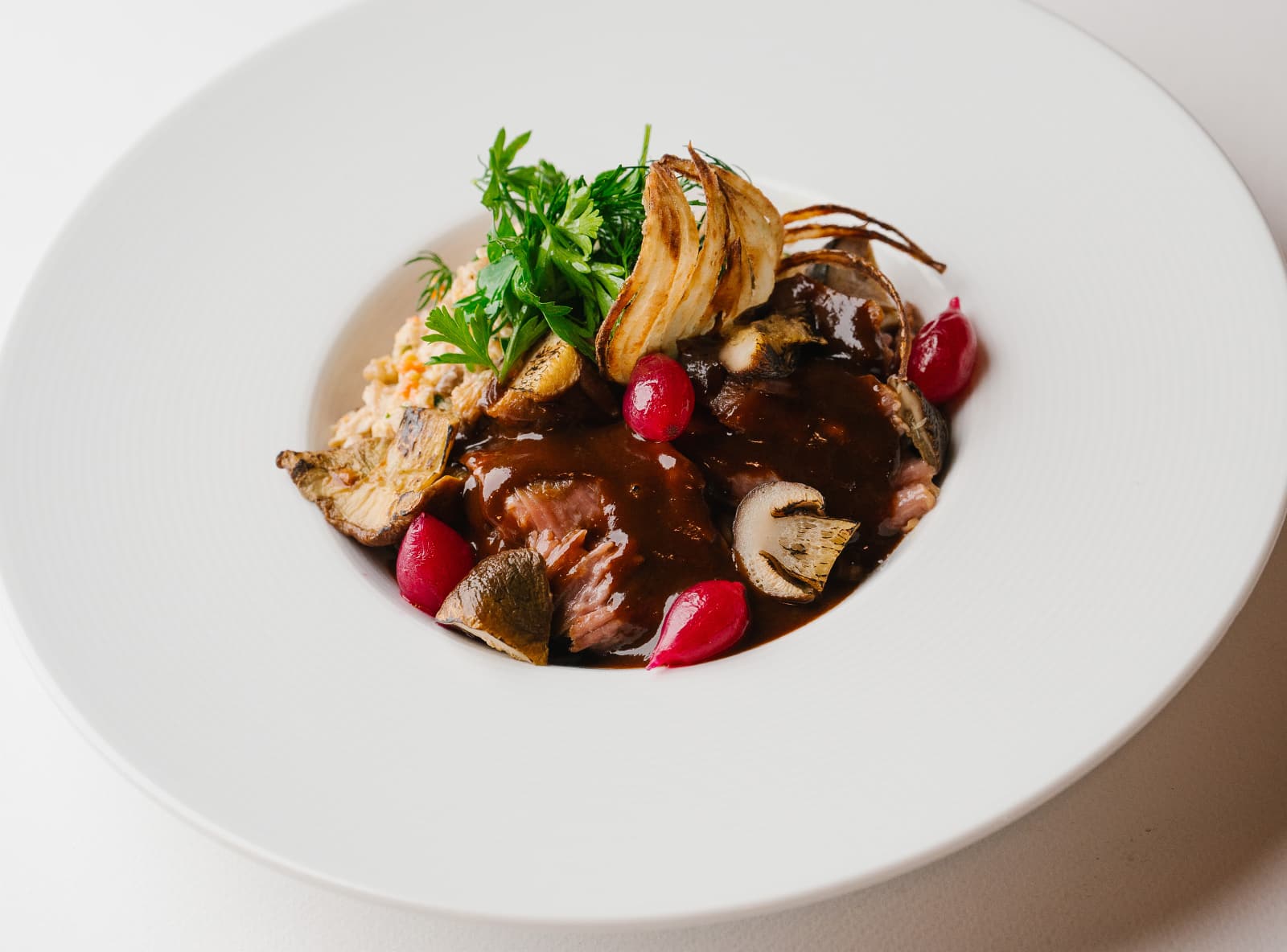 Томлёная говяжья щека с белыми грибами, кремом из печёного лука-порея и зелёной гречкой